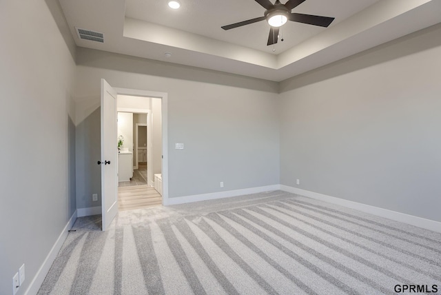 carpeted spare room featuring a raised ceiling and ceiling fan