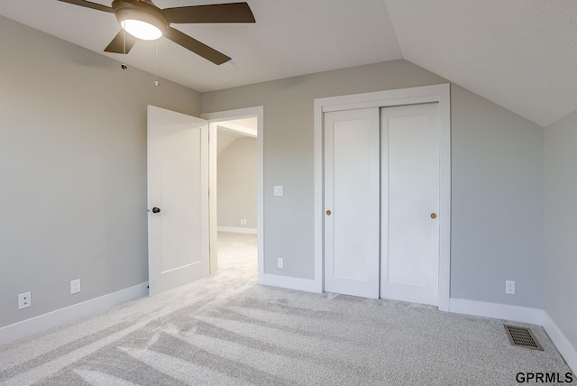 unfurnished bedroom with lofted ceiling, light colored carpet, a closet, and ceiling fan