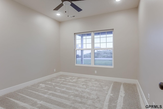 empty room featuring a water view, carpet, and ceiling fan