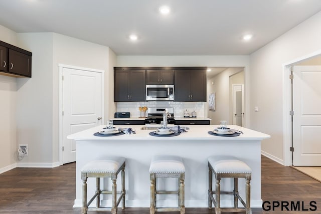 kitchen featuring a breakfast bar, sink, tasteful backsplash, appliances with stainless steel finishes, and an island with sink