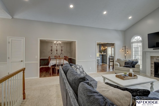 living room with high vaulted ceiling, a brick fireplace, light carpet, and an inviting chandelier