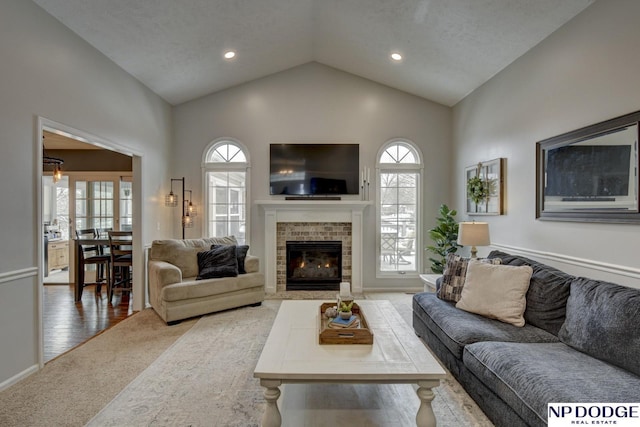 living room featuring lofted ceiling, a fireplace, and carpet