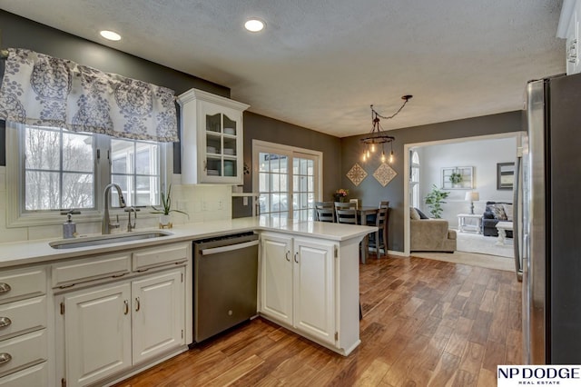 kitchen with sink, white cabinetry, kitchen peninsula, pendant lighting, and stainless steel appliances