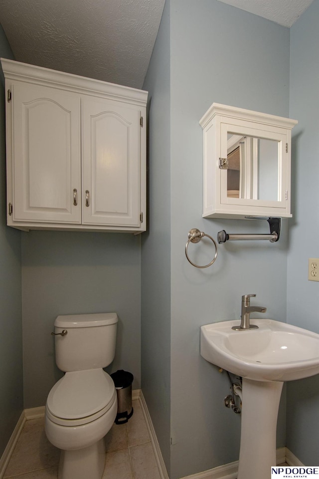 bathroom featuring toilet, tile patterned flooring, and a textured ceiling