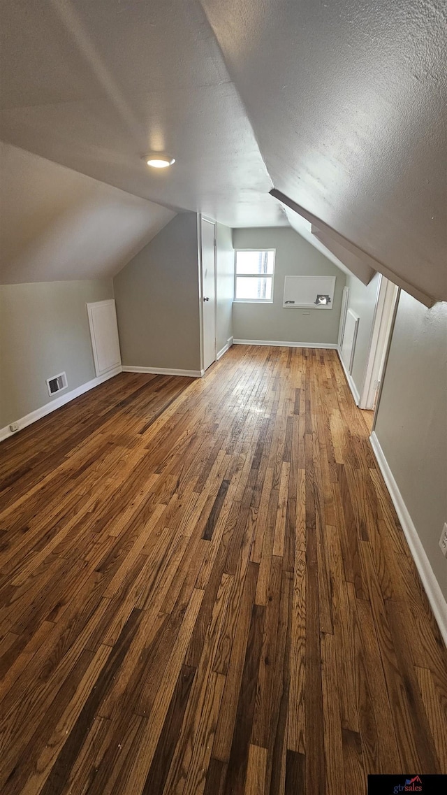 bonus room with dark hardwood / wood-style flooring, lofted ceiling, and a textured ceiling