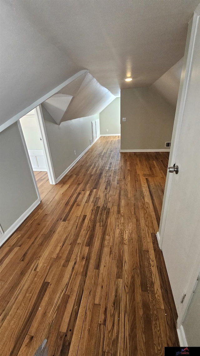 bonus room featuring wood-type flooring, lofted ceiling, and a textured ceiling