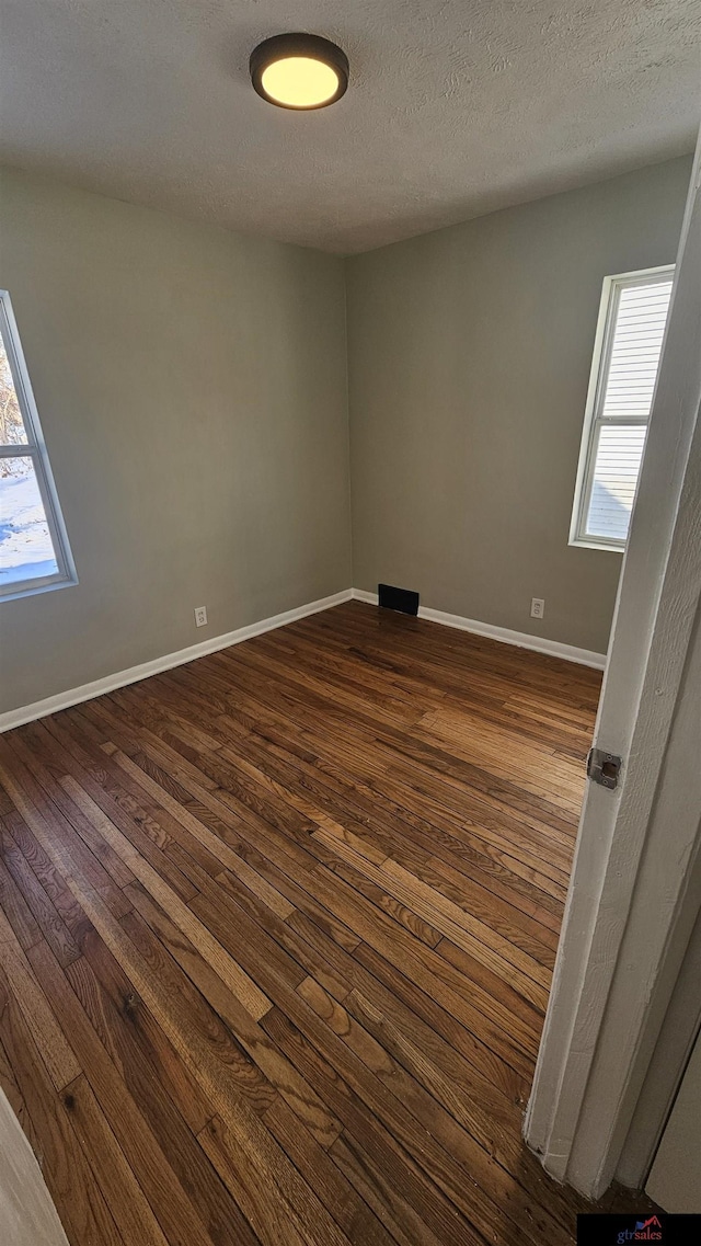 spare room featuring dark hardwood / wood-style flooring and a textured ceiling