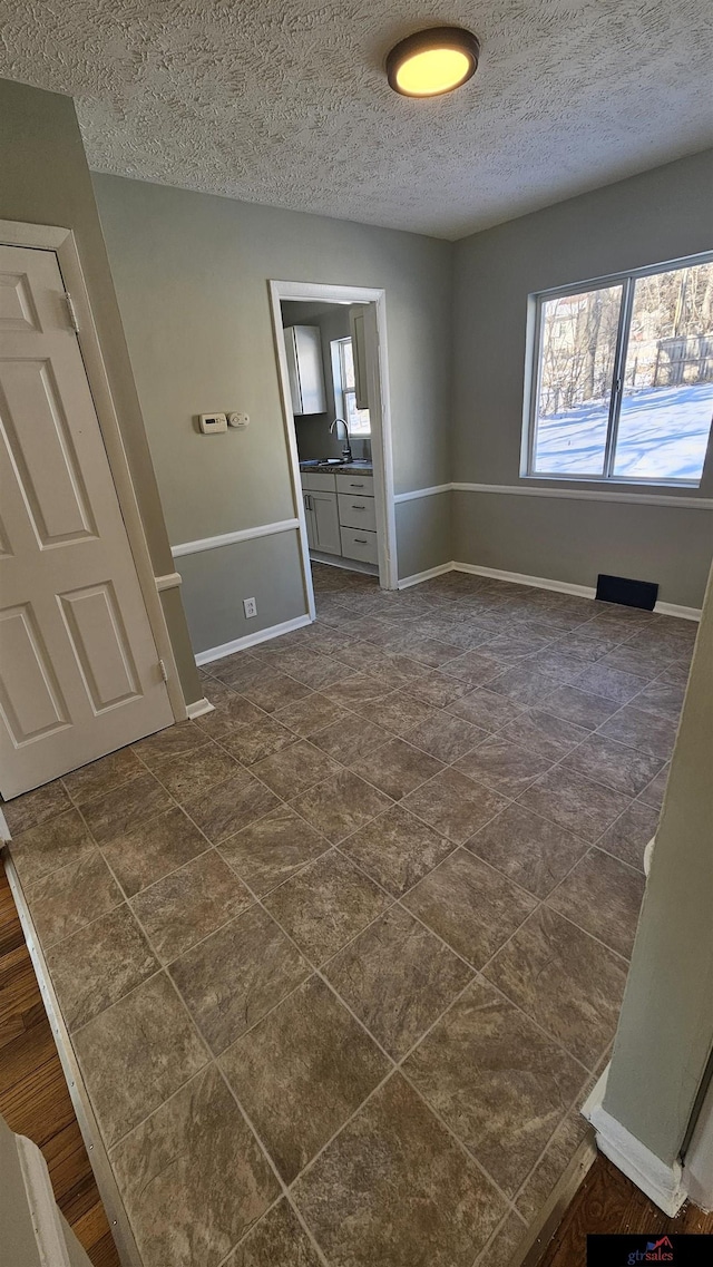 unfurnished room with sink and a textured ceiling