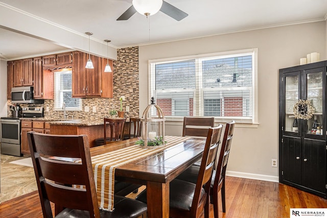 dining space with ornamental molding, wood finished floors, and baseboards