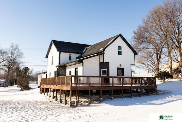 snow covered house with a wooden deck