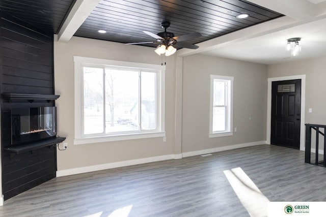 unfurnished living room with a large fireplace, hardwood / wood-style floors, wood ceiling, and beam ceiling