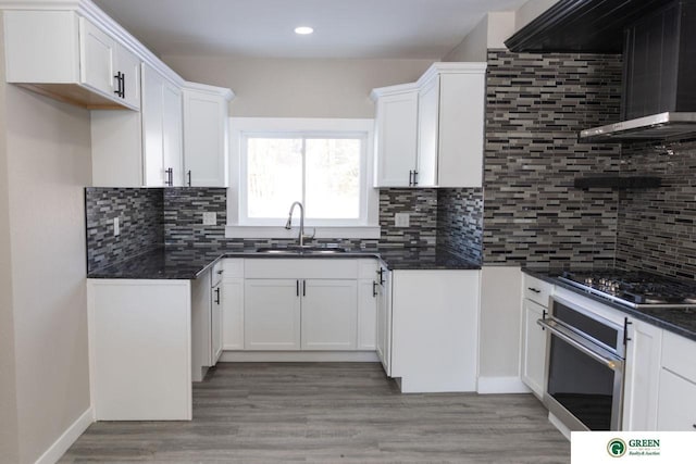 kitchen featuring sink, appliances with stainless steel finishes, tasteful backsplash, white cabinets, and wall chimney exhaust hood