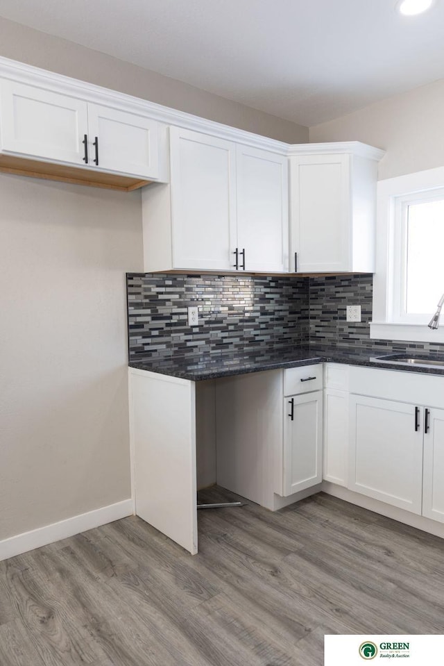 kitchen featuring white cabinetry, sink, backsplash, and hardwood / wood-style floors