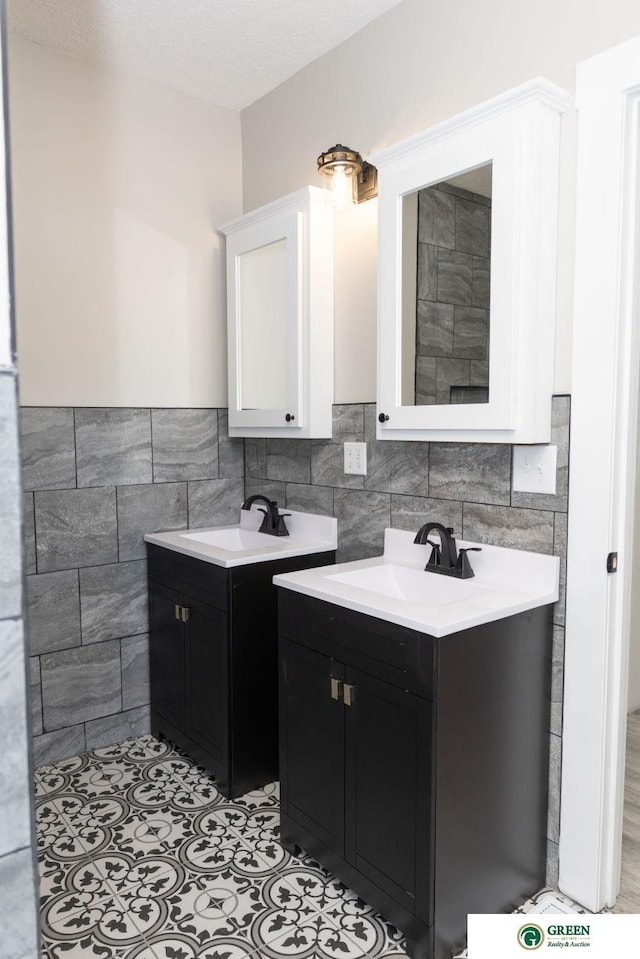 bathroom with vanity, a textured ceiling, tile patterned floors, and tile walls