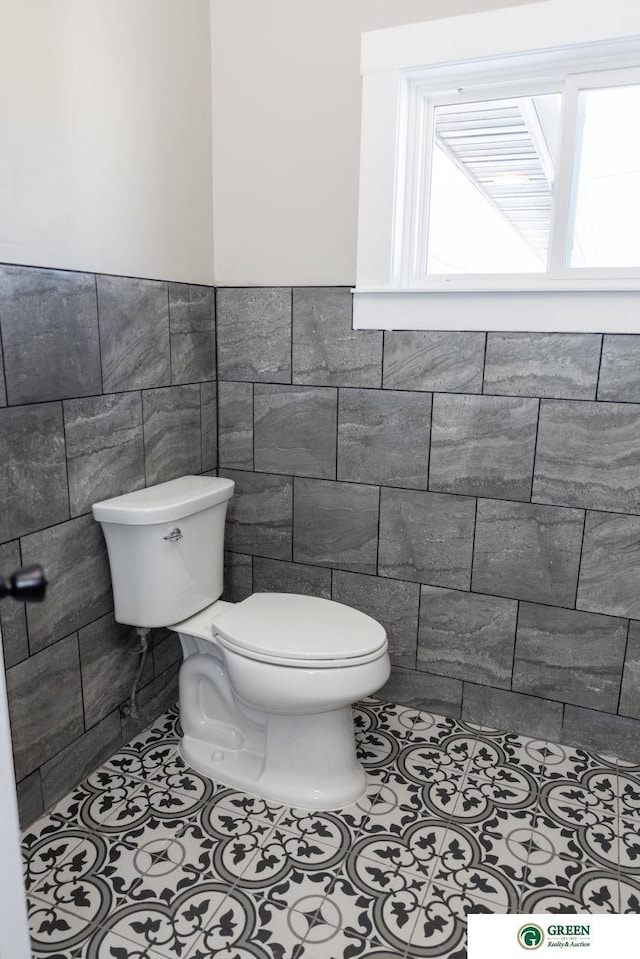 bathroom featuring tile patterned flooring, tile walls, and toilet