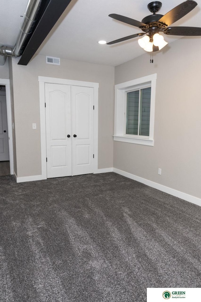 unfurnished bedroom featuring dark colored carpet, ceiling fan, and a closet