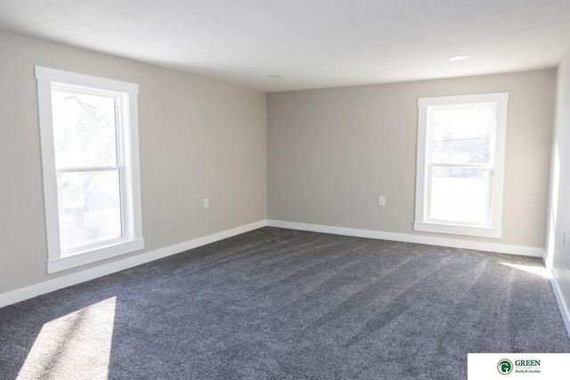 empty room with dark colored carpet and a healthy amount of sunlight