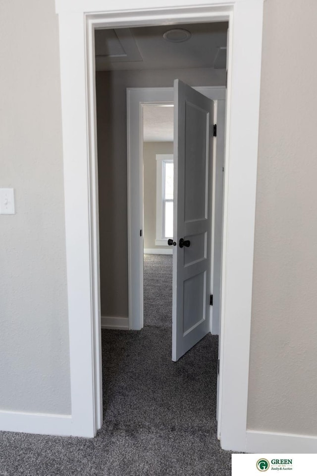 hallway with dark colored carpet