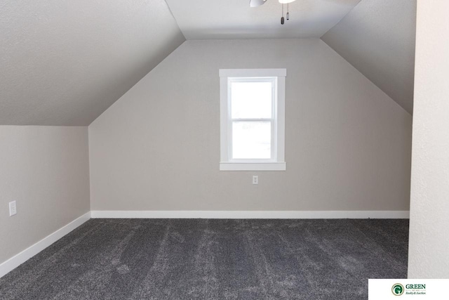 additional living space with ceiling fan, vaulted ceiling, and dark colored carpet