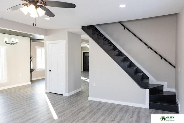 stairs featuring wood-type flooring and ceiling fan with notable chandelier