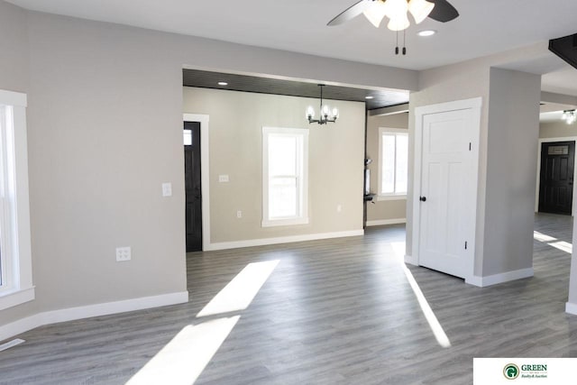 interior space with ceiling fan with notable chandelier and dark wood-type flooring