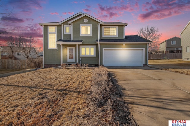 traditional-style home featuring concrete driveway, an attached garage, and fence