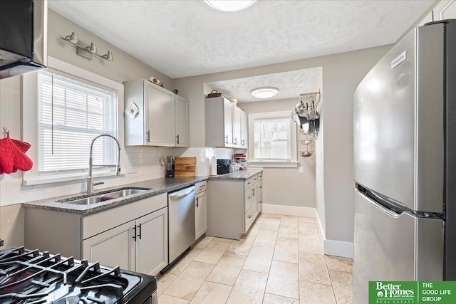 kitchen featuring light tile patterned flooring, appliances with stainless steel finishes, sink, backsplash, and a textured ceiling