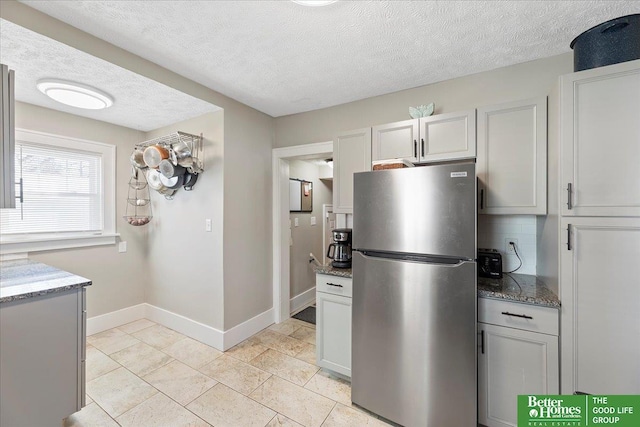 kitchen featuring white cabinetry, stainless steel refrigerator, and dark stone counters