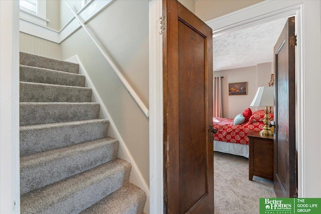 staircase featuring carpet and a textured ceiling