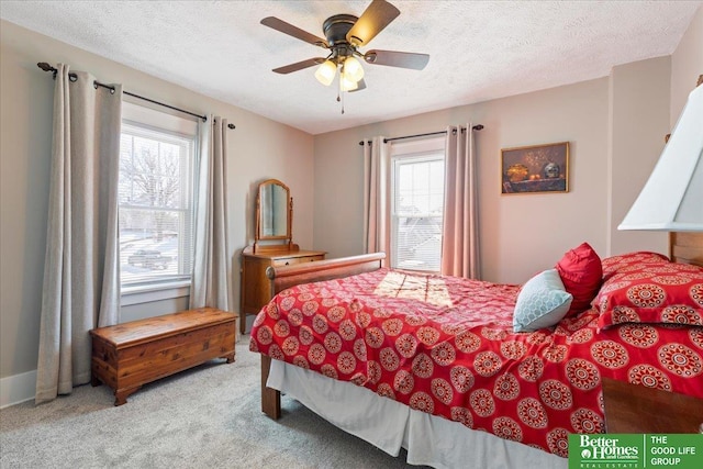 bedroom with ceiling fan, light carpet, and a textured ceiling