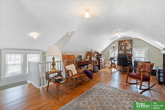 living area with hardwood / wood-style flooring, vaulted ceiling, and a textured ceiling