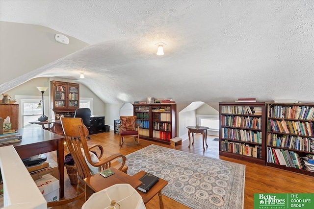 interior space with hardwood / wood-style flooring, vaulted ceiling, and a textured ceiling