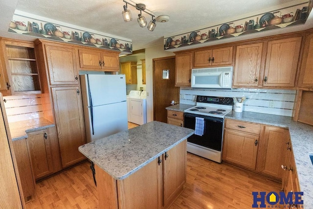 kitchen featuring a kitchen island, light wood-type flooring, washing machine and clothes dryer, and white appliances