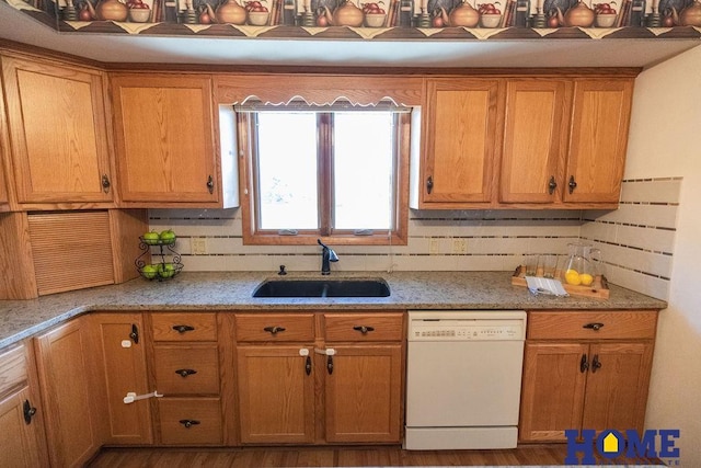 kitchen with light stone counters, dishwasher, sink, and decorative backsplash