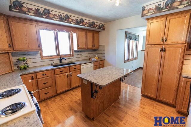 kitchen featuring sink, a kitchen breakfast bar, a center island, white dishwasher, and light wood-type flooring