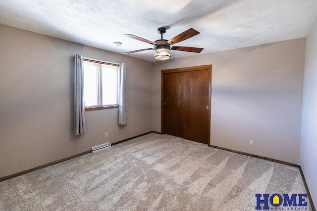 unfurnished bedroom with ceiling fan, light carpet, a textured ceiling, and a closet