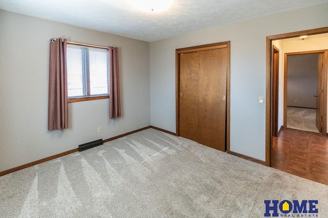 unfurnished bedroom with carpet floors, a closet, and a textured ceiling