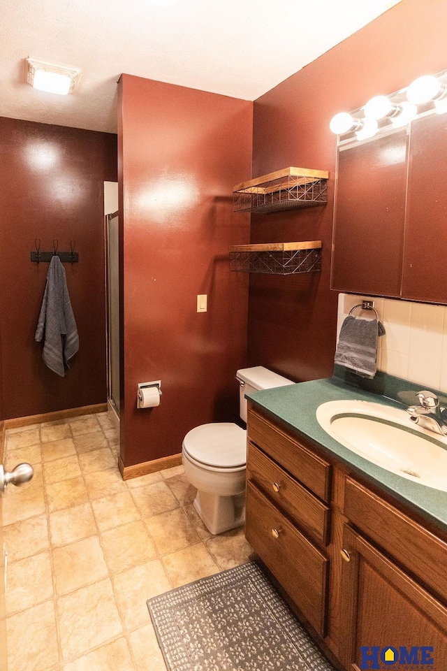 bathroom with vanity, toilet, and a shower with door