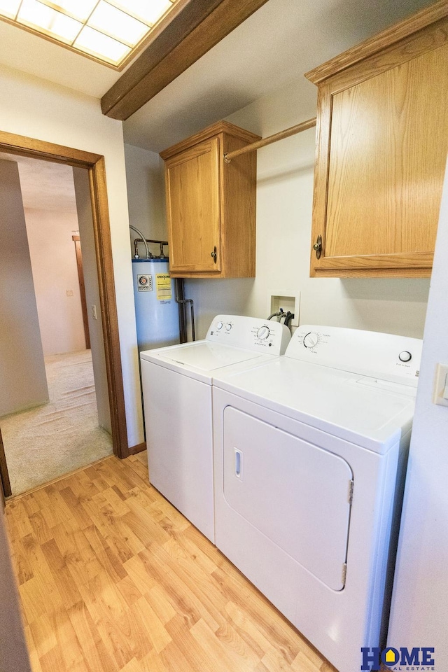 clothes washing area featuring light hardwood / wood-style flooring, cabinets, gas water heater, and washer and dryer