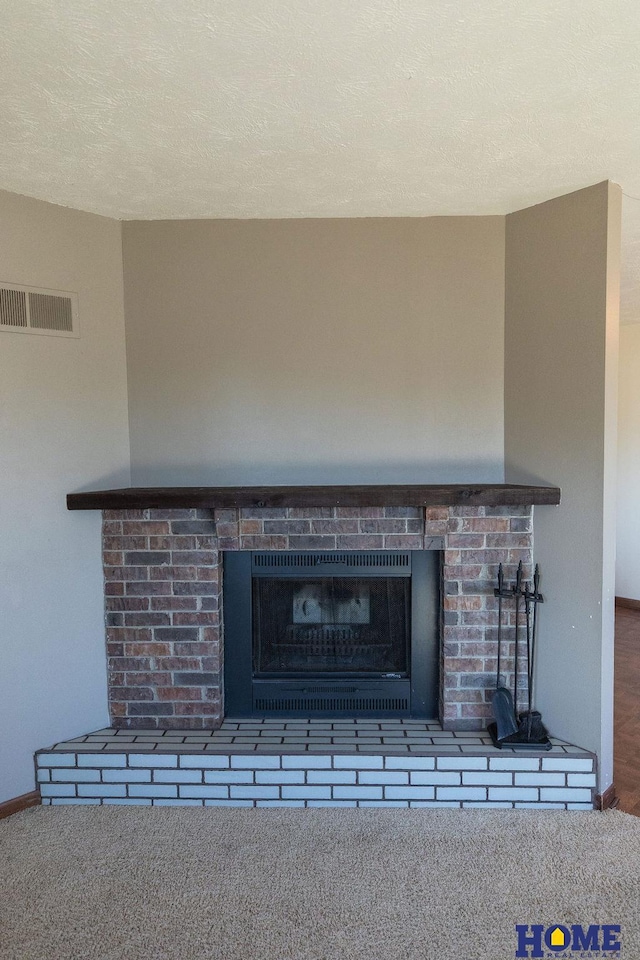 interior details featuring a fireplace, carpet floors, and a textured ceiling