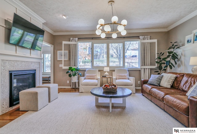 living room with an inviting chandelier, a fireplace, crown molding, and wood-type flooring