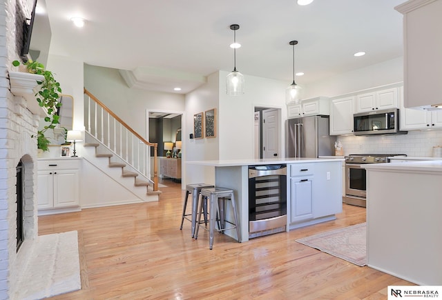 kitchen featuring a kitchen island, pendant lighting, white cabinetry, wine cooler, and stainless steel appliances