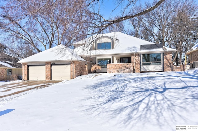 view of front facade with brick siding, a garage, and central AC