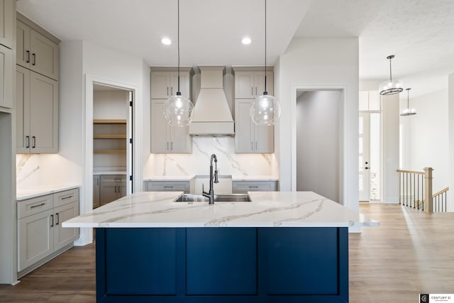 kitchen with a large island, sink, gray cabinetry, and premium range hood