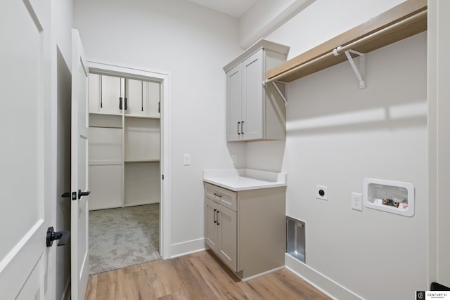 washroom featuring cabinets, hookup for an electric dryer, light hardwood / wood-style floors, and hookup for a washing machine