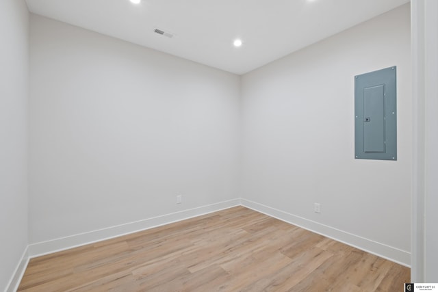 empty room featuring electric panel and light wood-type flooring