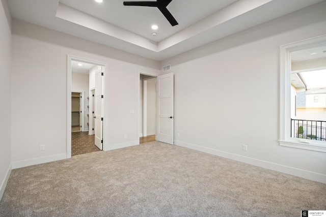 unfurnished bedroom with a raised ceiling, carpet floors, and ceiling fan