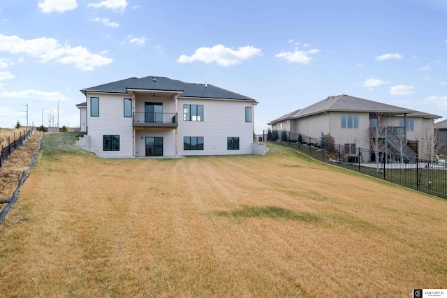 rear view of house with a lawn and a balcony