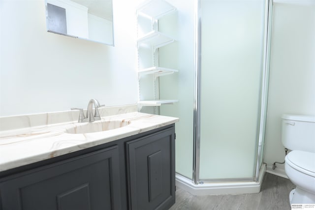 bathroom featuring hardwood / wood-style floors, vanity, toilet, and a shower with shower door