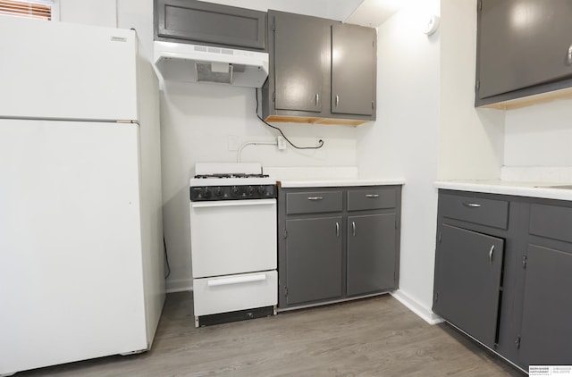 kitchen featuring gray cabinetry, hardwood / wood-style floors, and white appliances